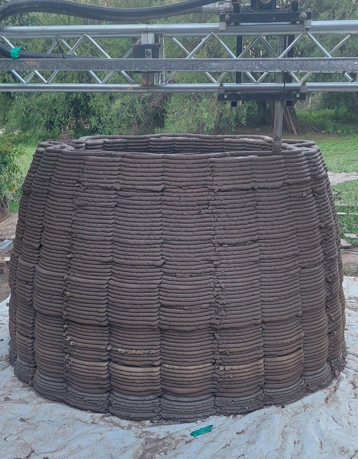 Estructura impresa en tierra bajo el sistema robótico durante el proceso constructivo